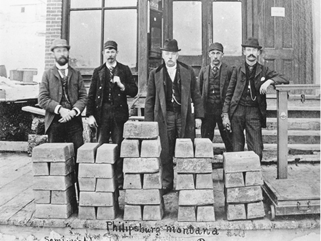 Five men standing behind stacks of silver bullion bars